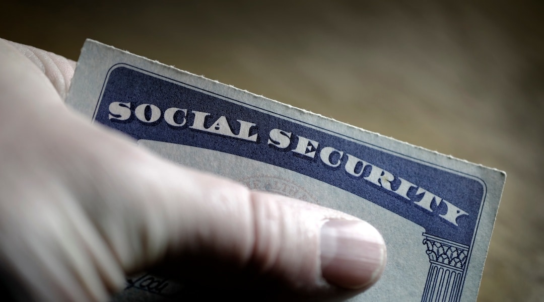 hand holding social security card; representing when should I take social security