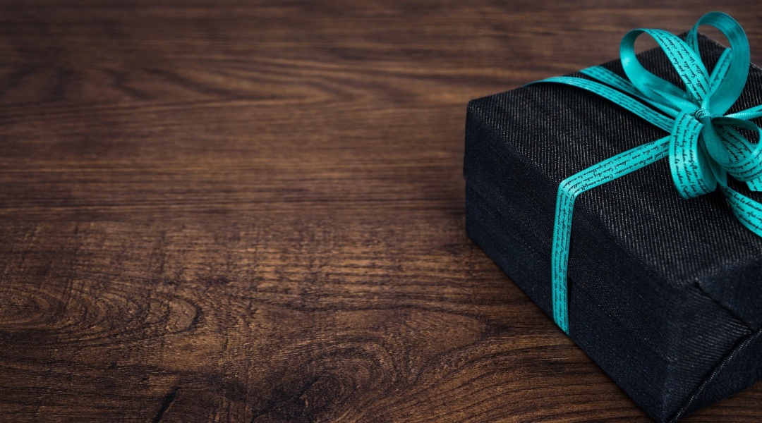 Black box with blue ribbon sitting on desk top, representing the Gift Tax